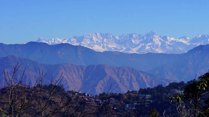 Snow-capped Himalayan range towering above rolling foothills and a small hill town