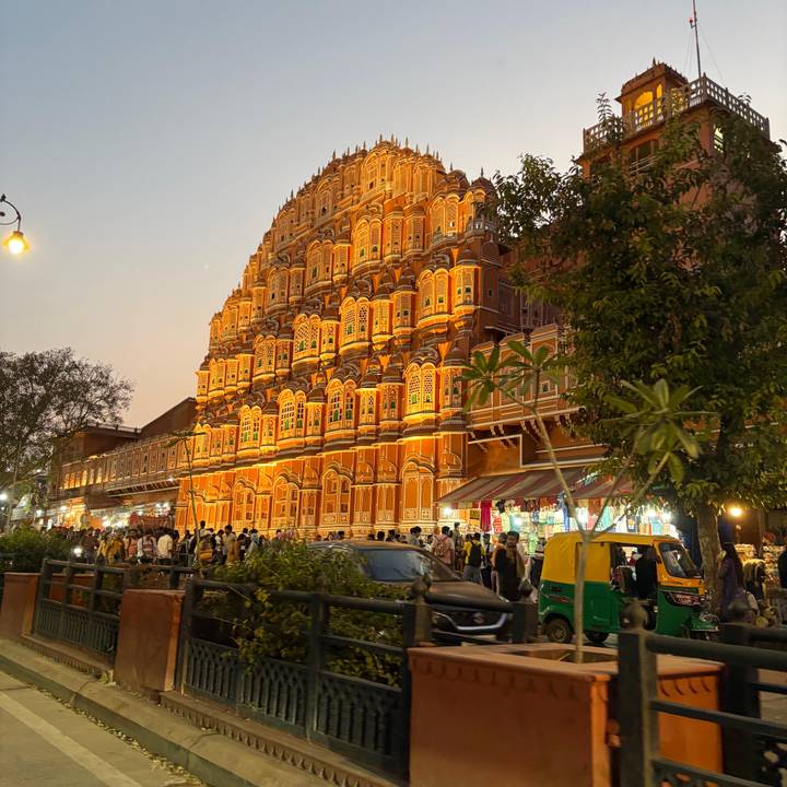 Evening crowd passes beneath the glowing orange windows of Jaipur's Hawa Mahal.