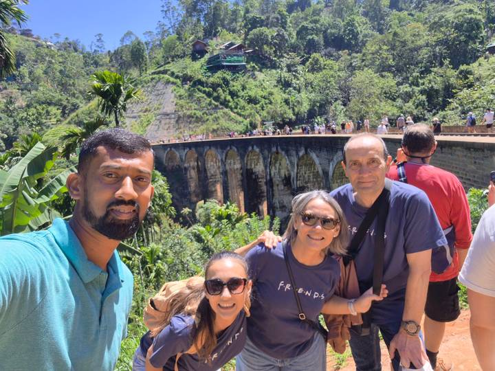 Selfie group in front of the iconic Nine-Arch Railway Bridge amid lush jungle.