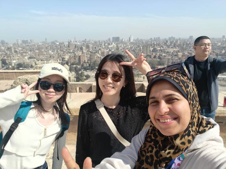 Selfie of friends flashing peace signs with sprawling Cairo skyline behind them.
