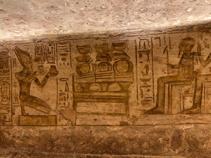 Detailed ancient Egyptian wall reliefs and hieroglyphs in warm interior lighting.