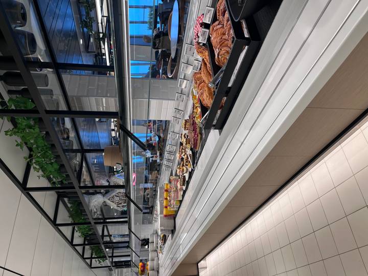 Modern self-service buffet counter lined with pastries, juices and breakfast items.