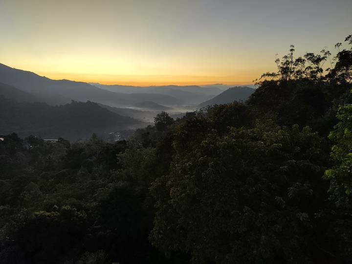 Misty mountain valleys at dawn with golden horizon and layers of rolling hills and forest canopy.