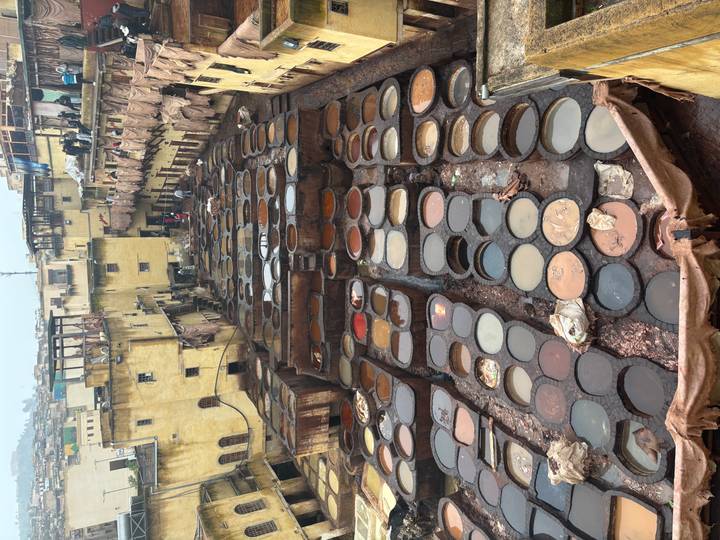 Aerial view of Fes tanneries with workers and rows of colorful stone dye vats.
