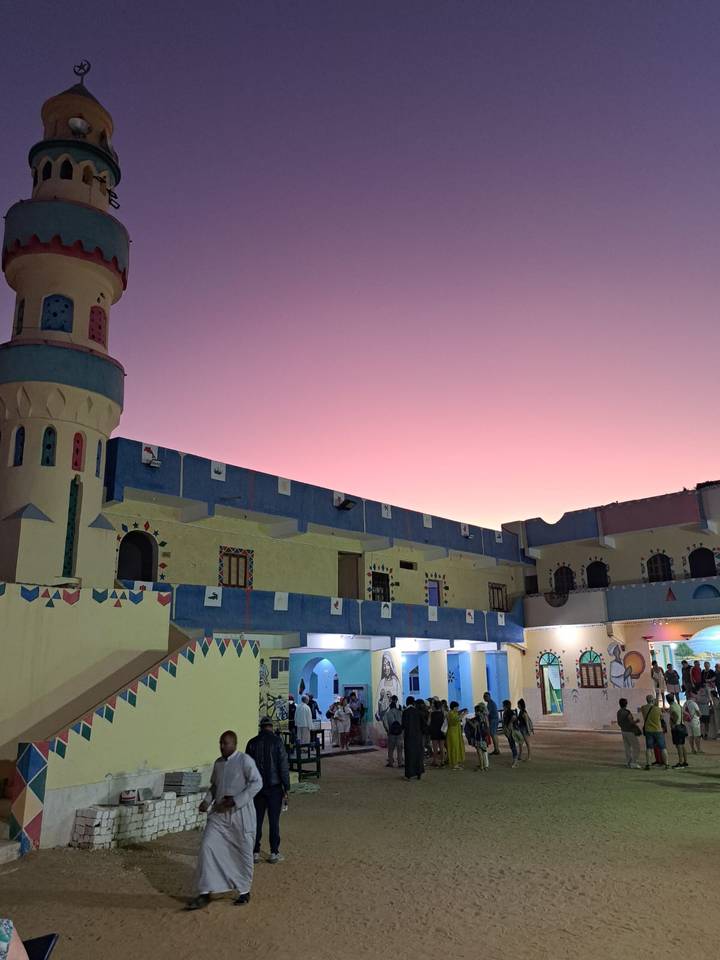 Colorful Nubian guesthouse courtyard glows under a violet twilight sky.