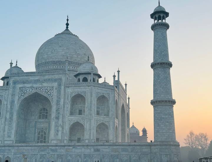 Side view of the Taj Mahal’s marble dome and minaret at pastel sunrise light.