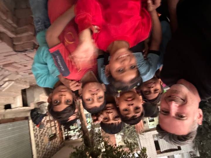 Traveler surrounded by smiling local children, some motion blur visible.