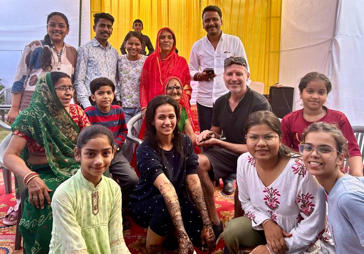 Group gathered at a festive event with henna designs and bright clothing.
