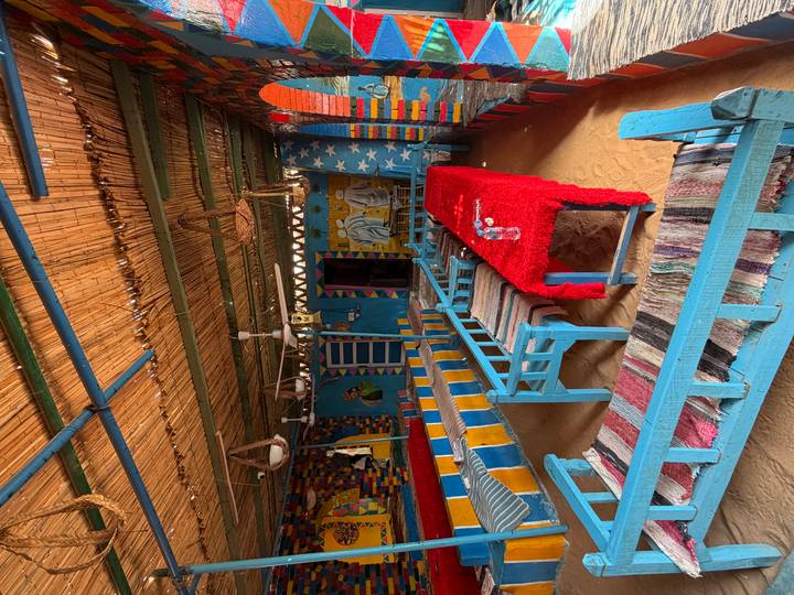 Color-saturated Nubian style café with blue benches and sand floor.