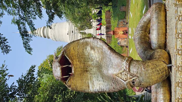 Huge woven cobra sculpture guards the approach to a white stupa at Wat Phnom.