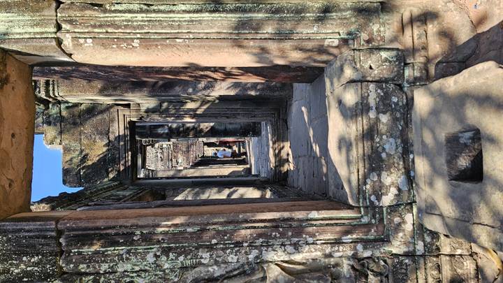 Stone corridor framed by multiple doorways creates a depth effect at Angkor ruins.