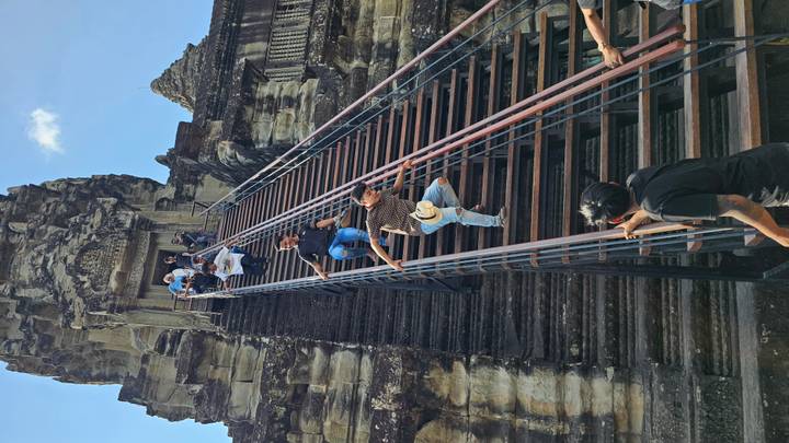 Tourists carefully descend the vertiginous staircase of Angkor Wat’s central tower.