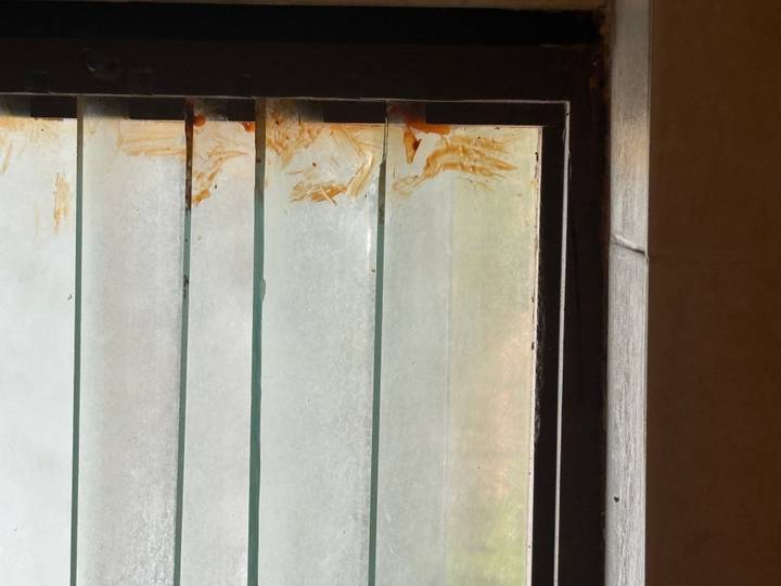 Bathroom louvre window with grime and rust-stained edges.