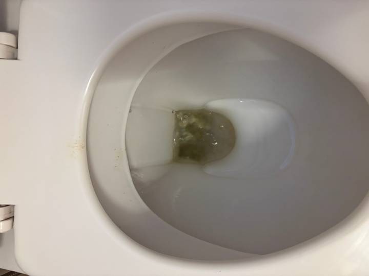 Toilet bowl mid-flush with discolored water.