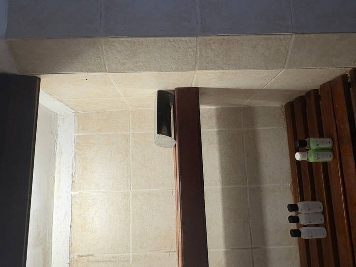 Shower shelf with stone block above small toiletry bottles in tiled cubicle.