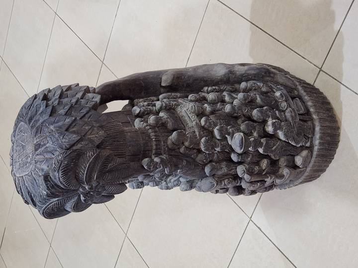 Intricate carved wooden sculpture displayed on tiled floor.