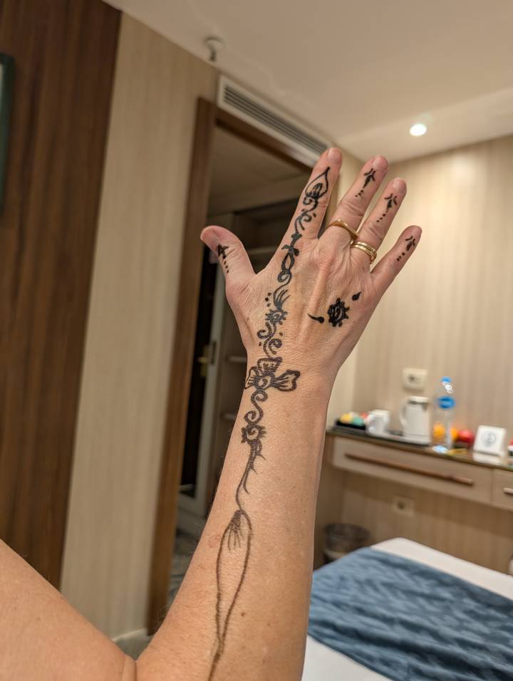 Hand with fresh black henna designs photographed indoors.