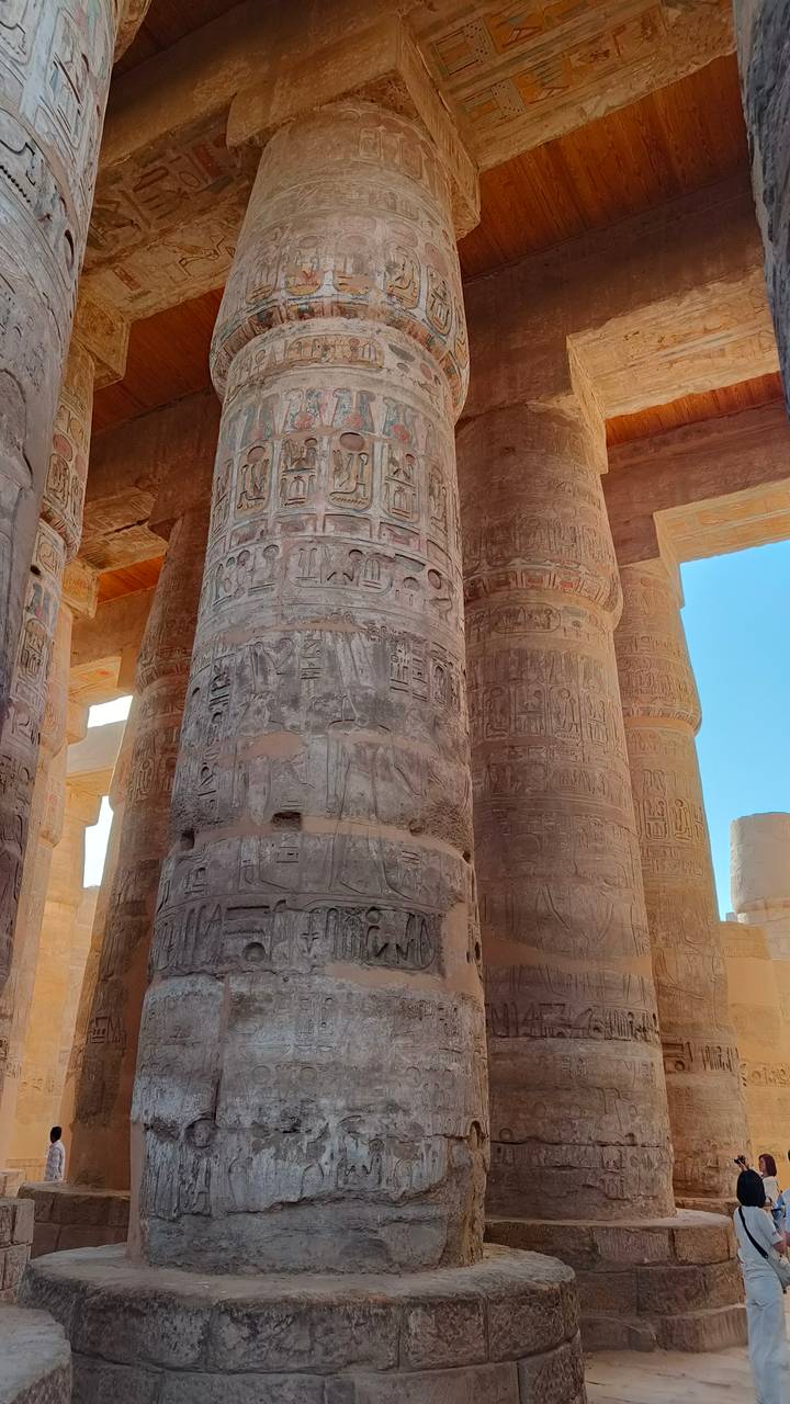 Close view of hieroglyph-covered sandstone columns under bright blue sky at Karnak.