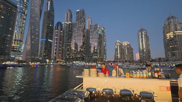Evening buffet set up on a cruise boat with Dubai Marina’s illuminated skyscrapers in the background.