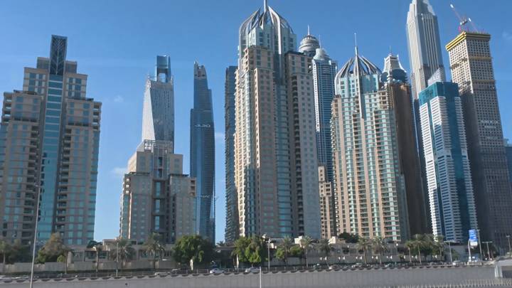 Cluster of modern skyscrapers rising against a bright blue Dubai sky.
