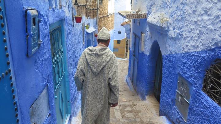 Person walking through the blue-painted streets of Chefchaouen.