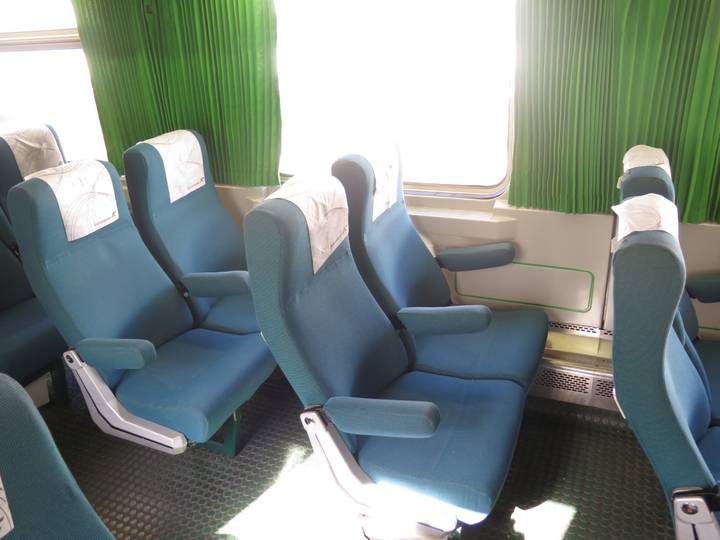 Empty train seats with green curtains.