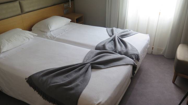 Twin beds with neatly folded blankets in a tidy hotel room.