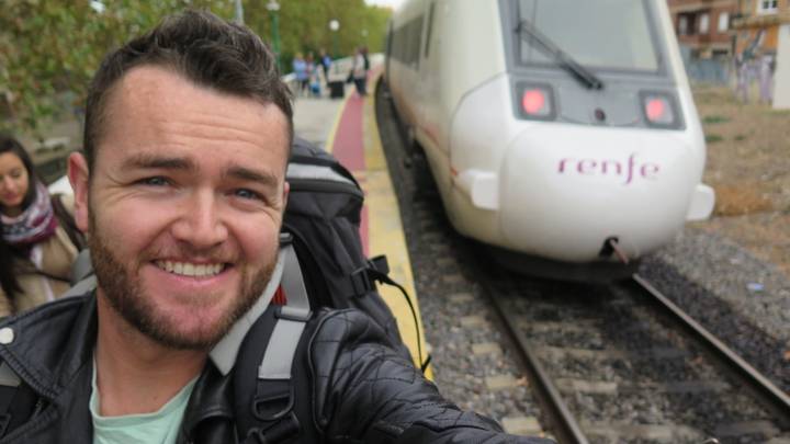 Man taking a selfie on a train platform beside a Renfe train.