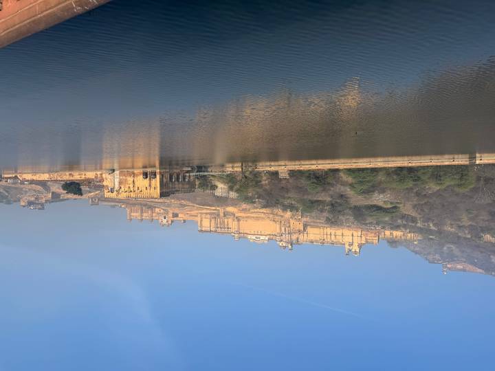 Amber Fort’s expansive sandstone façade reflected in Maota Lake on a hazy morning.