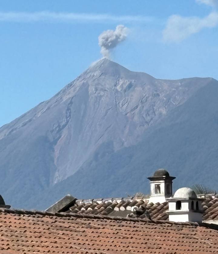 Historic rooftop with a looming volcano peak under clear blue sky