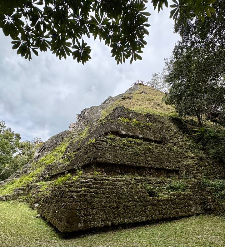 Lushly overgrown stone pyramid structure rising toward a cloudy sky in the jungle