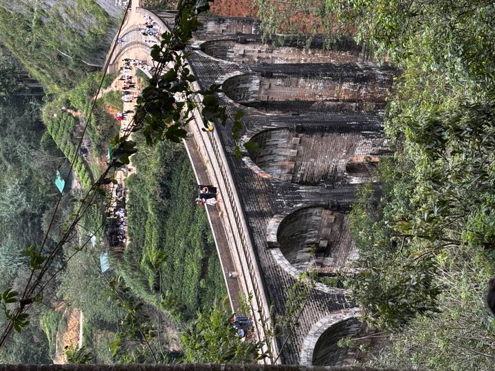 Crowds walking atop Sri Lanka’s scenic Nine-Arch Railway Bridge surrounded by lush jungle
