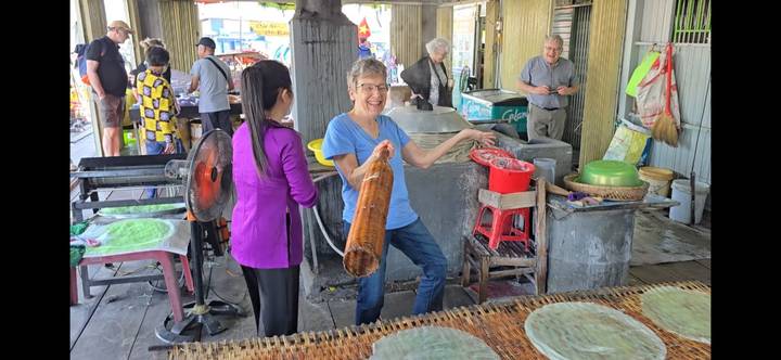 Smiling visitor holding a roll of rice-paper in a Mekong Delta workshop