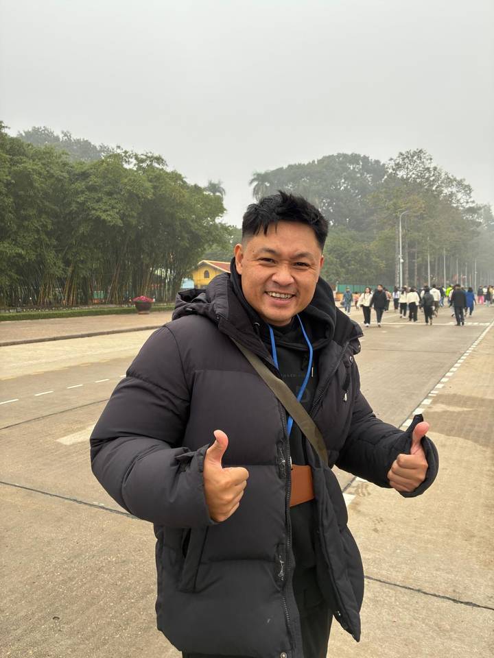 Portrait of a cheerful tour guide giving thumbs-up on a broad pedestrian avenue