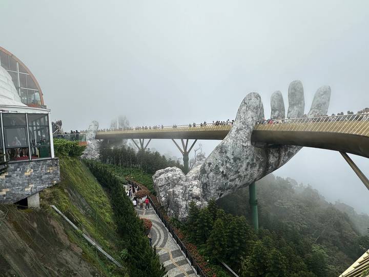 Iconic Golden Bridge at Ba Na Hills supported by giant stone hands shrouded in mist