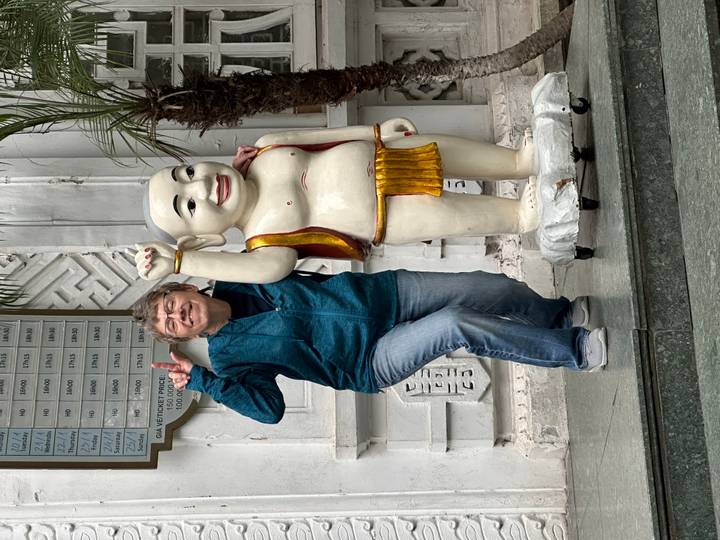Smiling traveler mimics a playful statue inside a Vietnamese temple courtyard