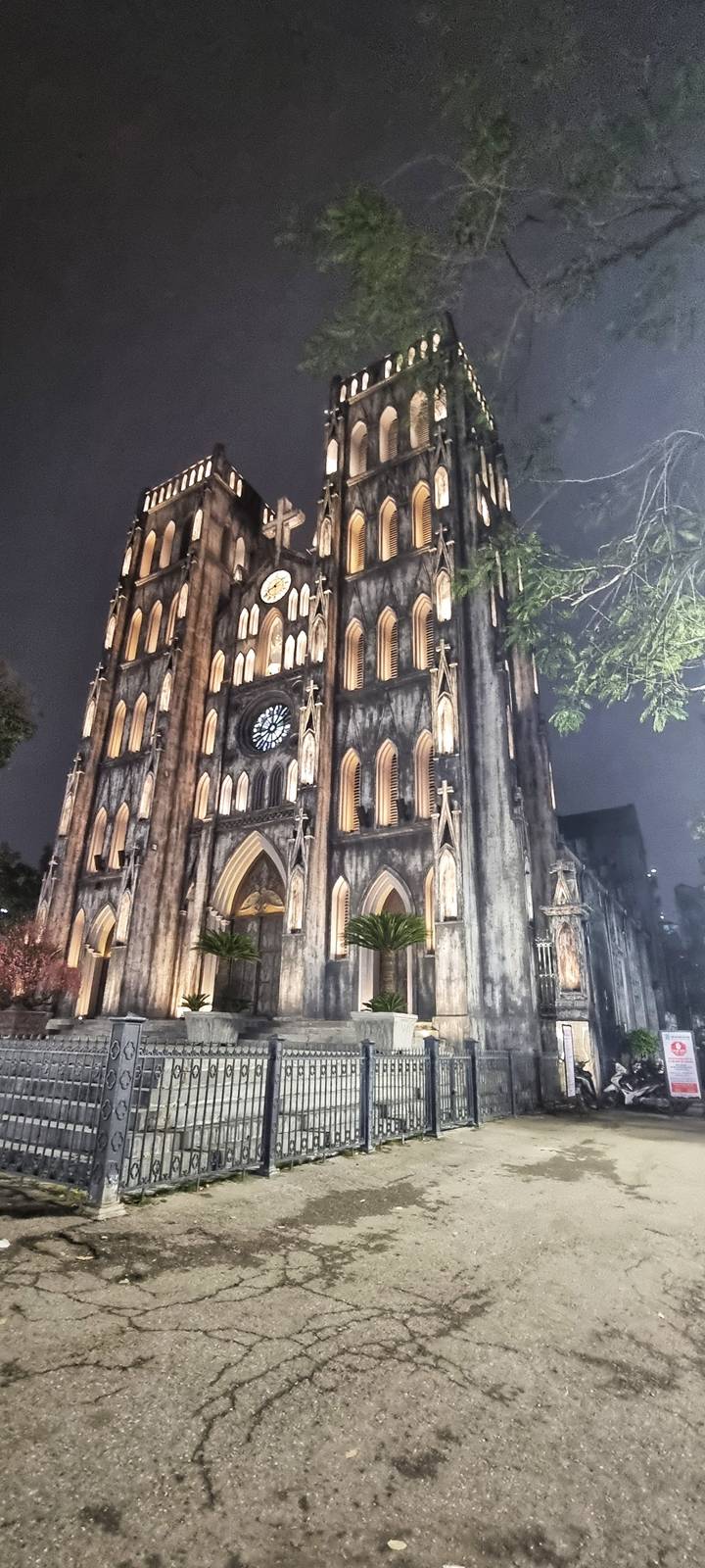 Neo-Gothic cathedral facade illuminated at night with pointed arches and a large rose window.
