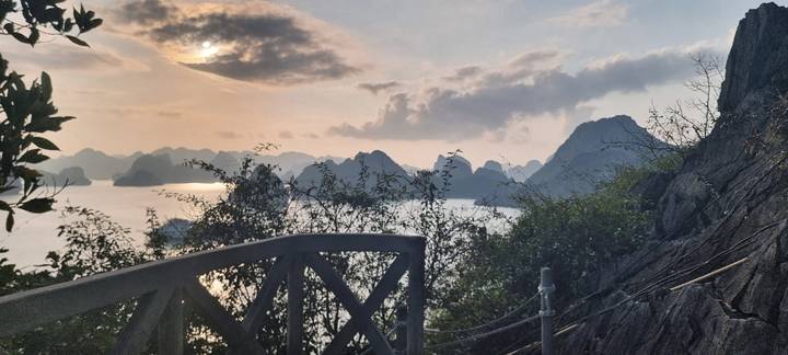 Dramatic sunset over Halong Bay’s karst islands viewed from a hilltop railing.