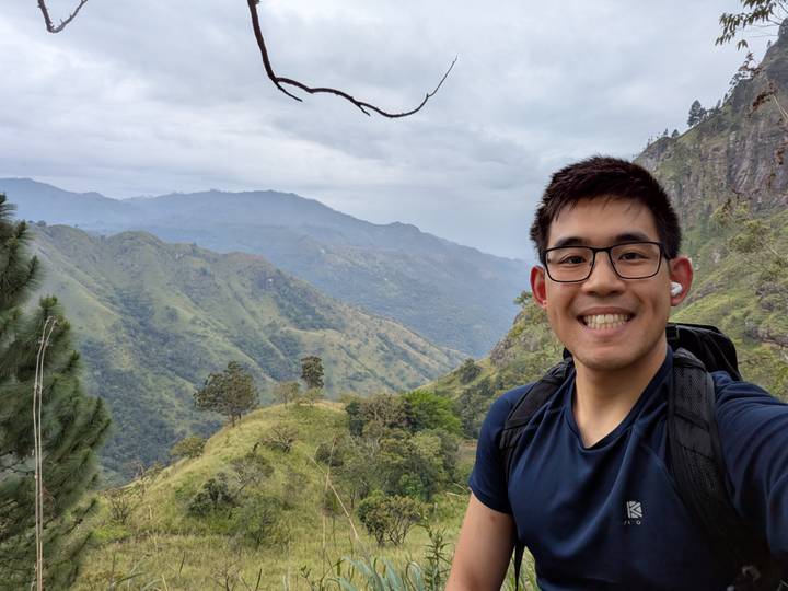 Hiker selfie overlooking misty green mountains and valleys.