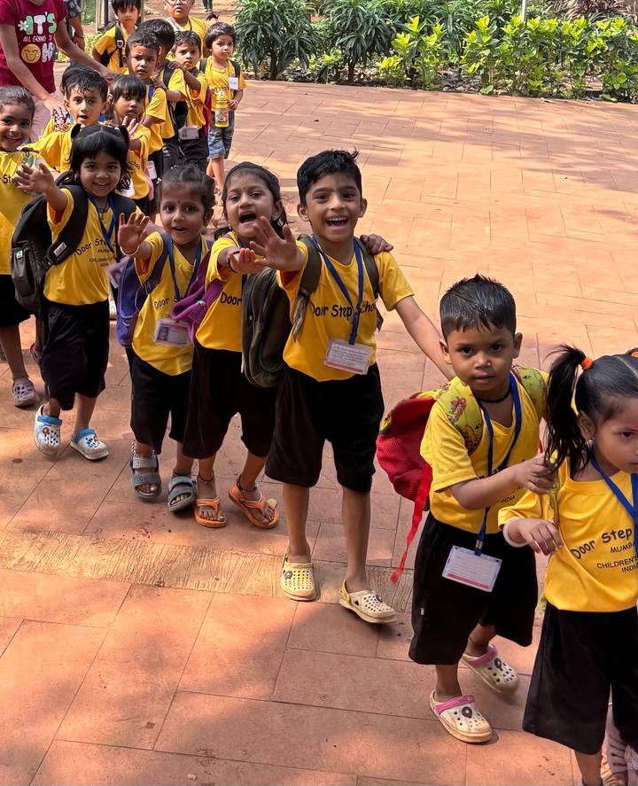 Line of enthusiastic schoolchildren in yellow uniforms reaching toward the camera