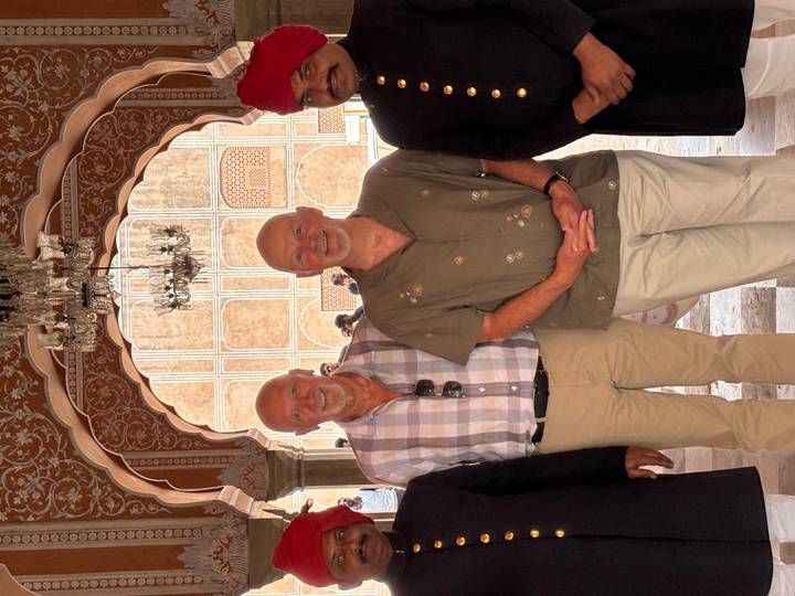 Visitors pose with palace official inside an ornately decorated Jaipur archway
