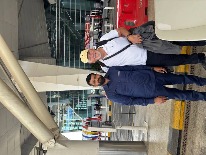 Traveler and driver smile outside a modern glass-fronted airport terminal