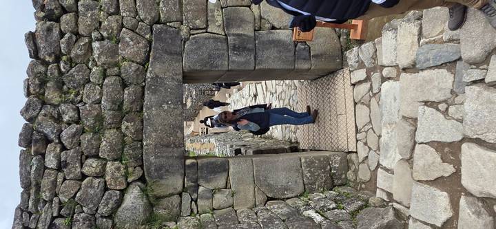 Visitor walks through a stone doorway amid ancient terraces of Machu Picchu