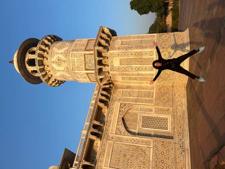 Traveler jumps joyfully before the ornate marble walls of the Baby Taj in Agra