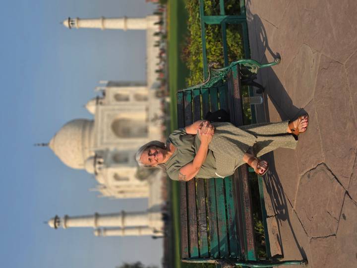 A visitor relaxes on a bench with the Taj Mahal perfectly framed in the background on a clear day.
