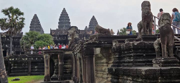 Visitors explore the ancient sandstone terraces and lion statues of Angkor Wat.