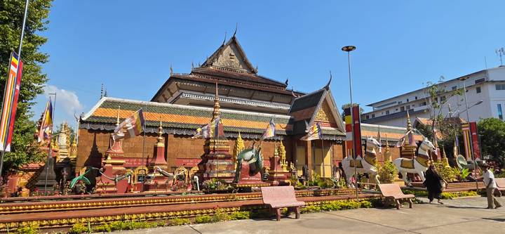 Colourful Cambodian pagoda complex with ornate stupas under a clear blue sky.
