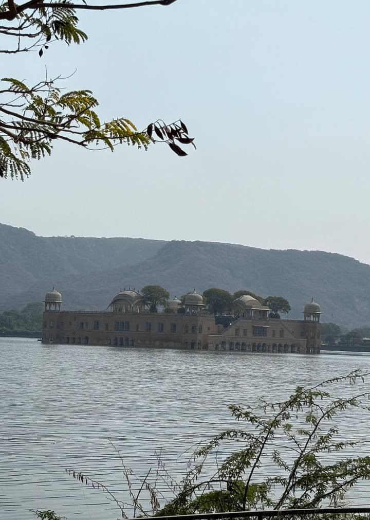 The Jal Mahal palace sits serenely in the middle of a lake against hazy Jaipur hills.