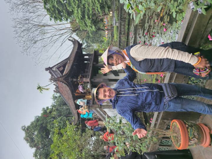 Smiling travellers pose in front of Hanoi's One Pillar Pagoda with a lotus pond in the foreground