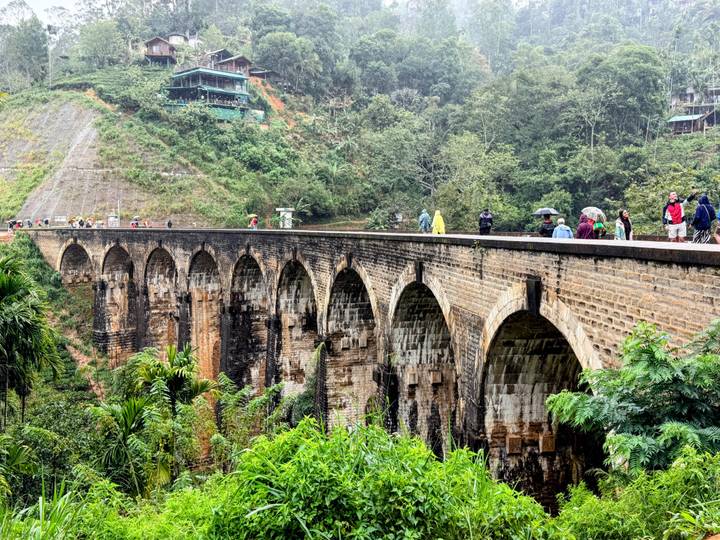 Visitors walk atop Sri Lanka’s iconic Nine-Arch Bridge surrounded by lush rainforest